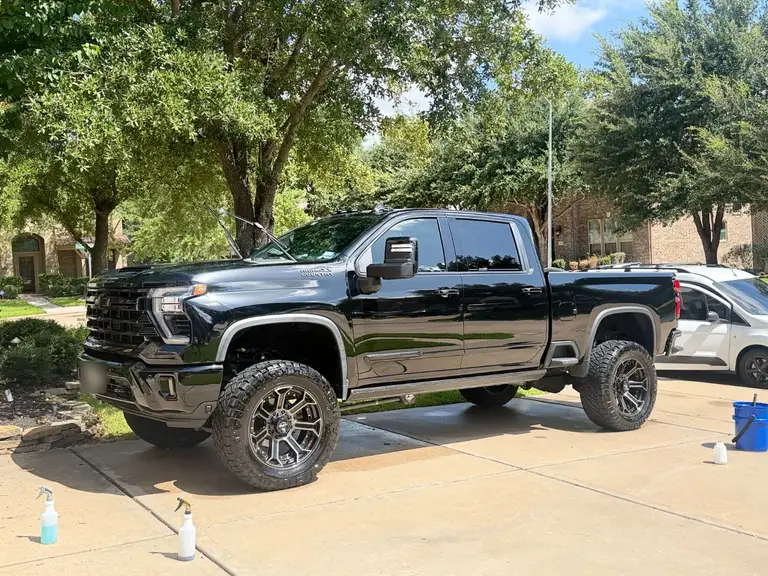 After: the customer's lifted Chevrolet Silverado 2500 High Country with a deep black gloss after mobile truck detailing